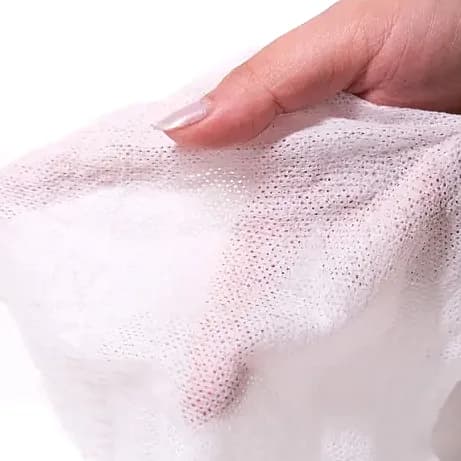 Elde açılmış beyaz dokusuz mendil, yarı şeffaf noktalı yüzey; promosyon ürünü
