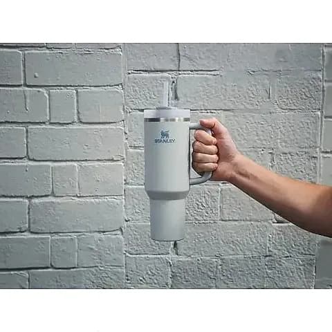 Promosyon açık gri termos bardak tuğla duvar önünde elde tutulurken, pipetli ve kulplu