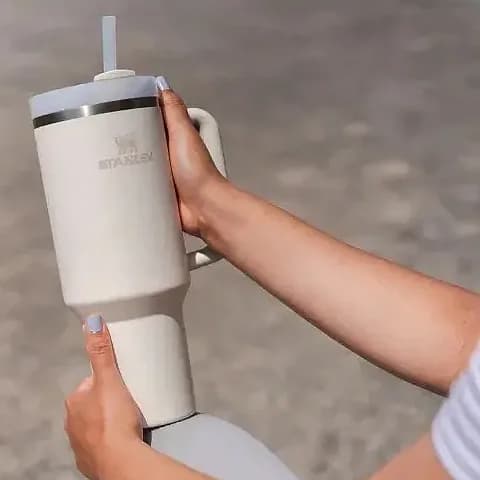 Promosyon krem termos bardak elde tutulurken, yan kulplu ve pipetli dış mekan kullanımı