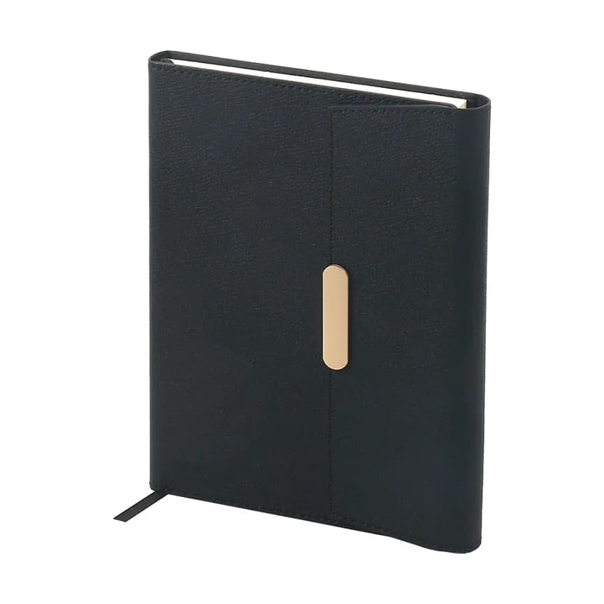 Siyah kapaklı defter; ön yüzde dikey şerit üzerinde altın tonlu oval kapama ve altta ince siyah kurdele.