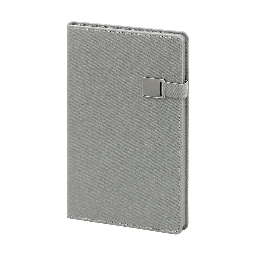 Açık gri kapaklı defter; ince dokulu mat yüzey, sağ kenarda elastik bant ve metalik dikdörtgen toka.