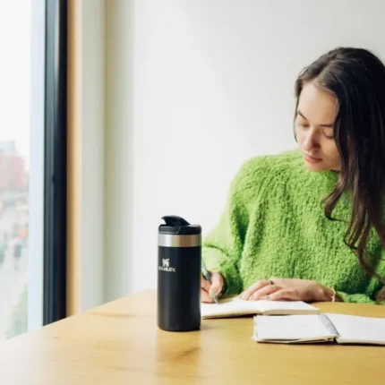 Stanley markası ile günlük kullanım ve outdoor aktiviteler için dayanıklı ve şık tasarım.|Şişirilmiş termos termosu ile kitap okuyan genç kadın